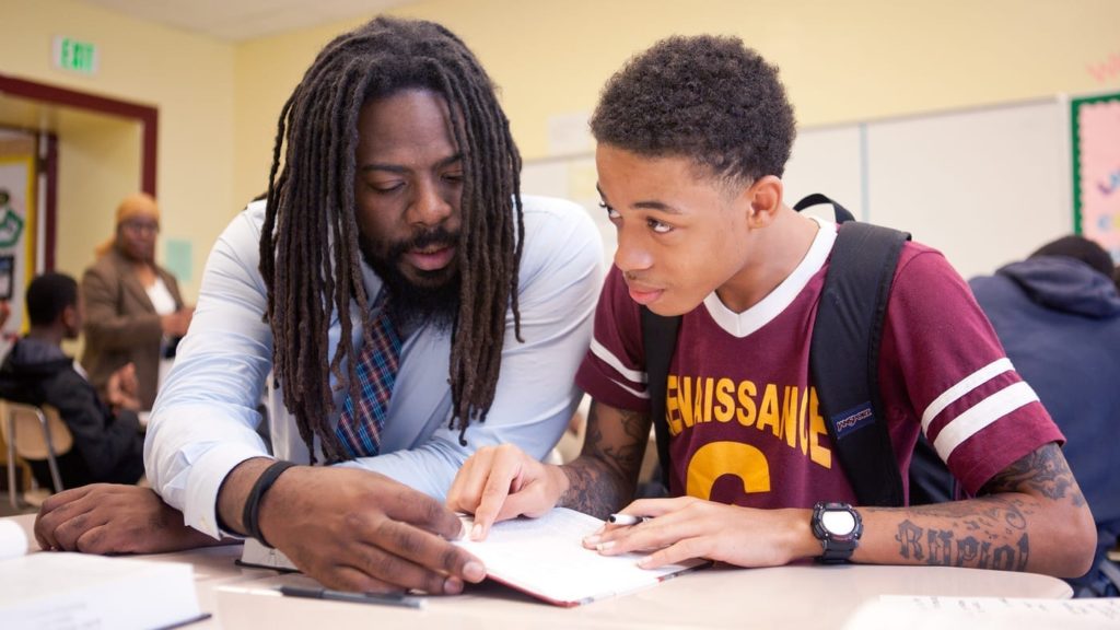 Mentor helps Black youth with schoolwork.